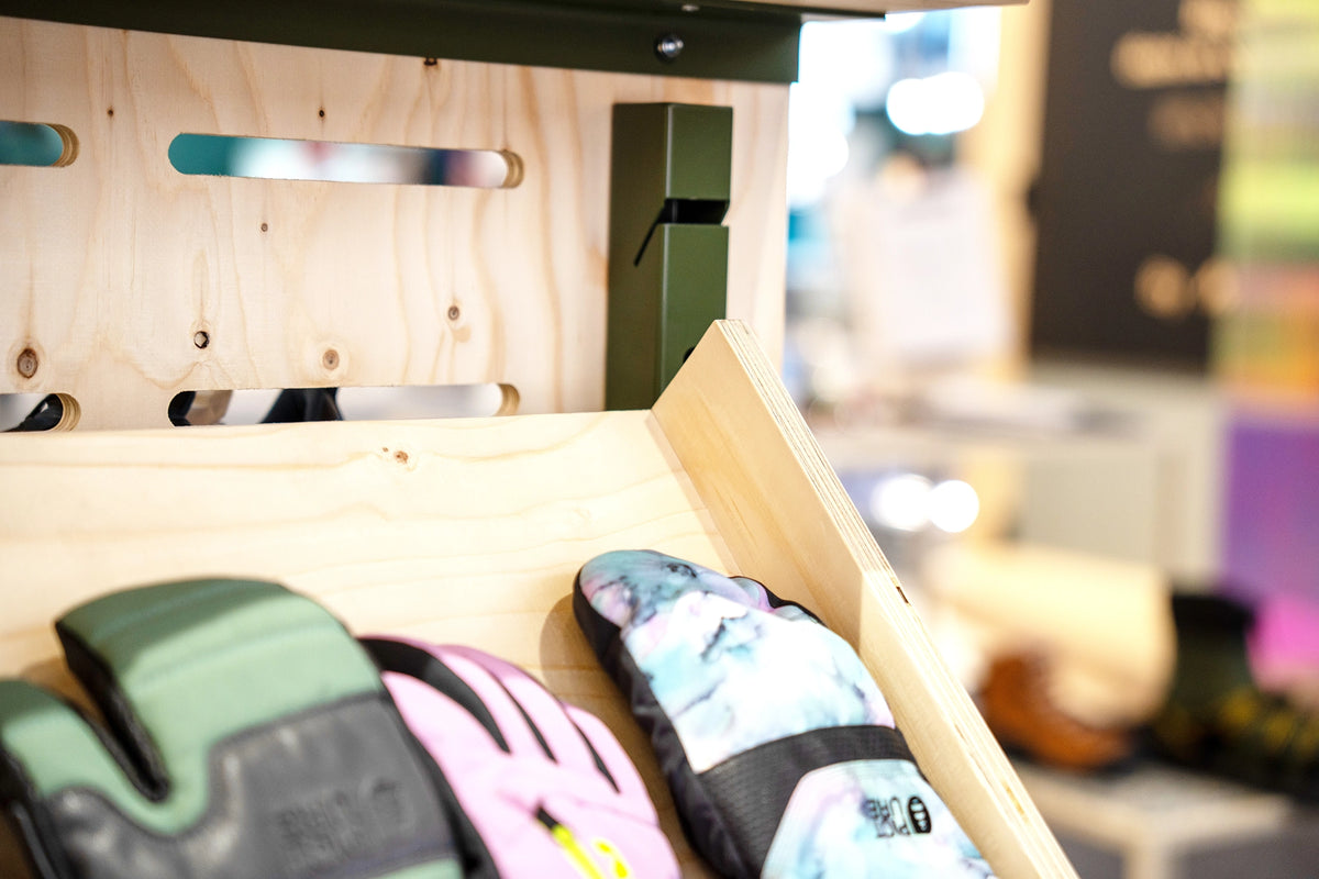 Accessoire de merchandising avec étagère en bois conçue pour la présentation de gants en magasin.